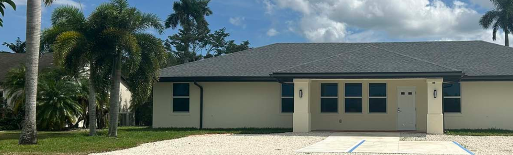 A beige student residence building on a sunny day with palm trees in the background.